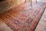 Antique Kerman rug's tattered side edge, dark blue, cochineal red, and ivory floral border.