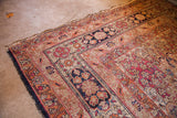 Antique Kerman rug's dark blue and cochineal floral border with visible tattered side cords.