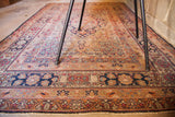 Antique Kerman rug's detailed dark blue floral border transitioning to ivory field patterns.