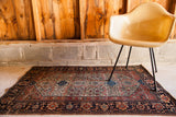 A collector's antique Farahan Sarouk rug styled with modern furniture for scale.