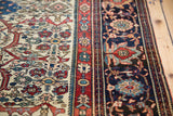 Intricate red and navy floral borders contrast with the ivory herati-patterned field of a Farahan Sarouk.