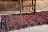 Antique Sarouk runner: coral field, unique perched bird motifs, dark blue border, and visible fraying.