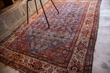 Fine Herati style rug corner, intricate floral motifs on indigo, red, and ivory borders.