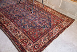 Herati style rug corner showing indigo blue field, intricate red and cream borders, new selvages.
