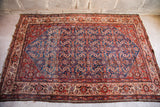 Fine village weave Herati rug corner, with intricate blue, red, and ivory floral patterns.
