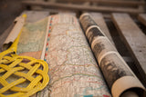Vintage battle map set showing a curled color map and a roll of black and white photographs.