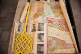 Colorful vintage battle maps and historical photographs from the set, shown partially unrolled.