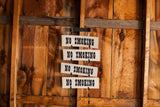 A grouping of vintage No Smoking signs shown in a vertical stacked display.