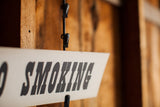 Vintage 'SMOKING' sign with bold black lettering on a white background.