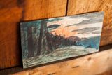 Angled view of vintage ink landscape drawing, showing green trees and orange sky.
