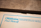 Close-up of the frayed top edge and blue title of the vintage Paul Metcalf poster.