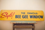 Mid century yellow Bee Gee sign, red and blue text, with visible paint chips.