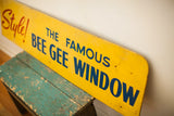 Distressed yellow Bee Gee Window sign with blue text, resting on a chippy teal stool.
