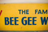 Mid Century Bee Gee sign detail: blue text on yellow, showing peeling paint and grit.