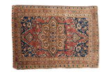 Antique Farahan Sarouk rug with a central medallion on a deep red field with dark blue and bronze accents.