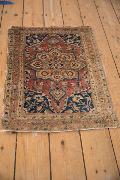 Angled view showing the complete design and storied character of the small antique Farahan rug.
