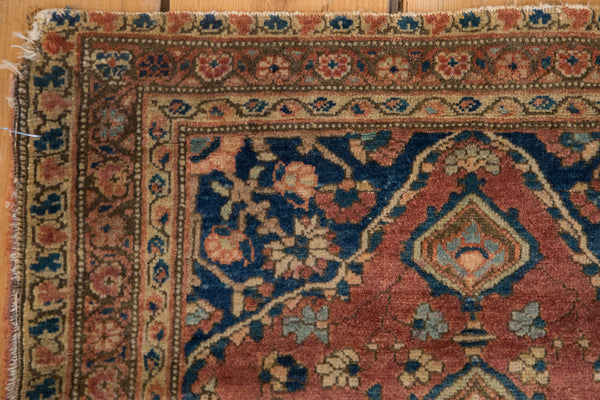 Corner detail of a collector Farahan Sarouk with storied wear and floral borders in red and blue.