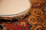 Intricate silver-plated foot with aged patina on the antique mirror stand's beveled edge.