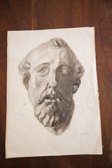 Faint artist signature and aged paper condition on a charcoal drawing of a Roman bust.