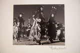 Artist's signature on mat board below black and white Native American dance photo.