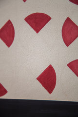 Cranberry red fan-shaped ink slices on textured paper with black mat detail.