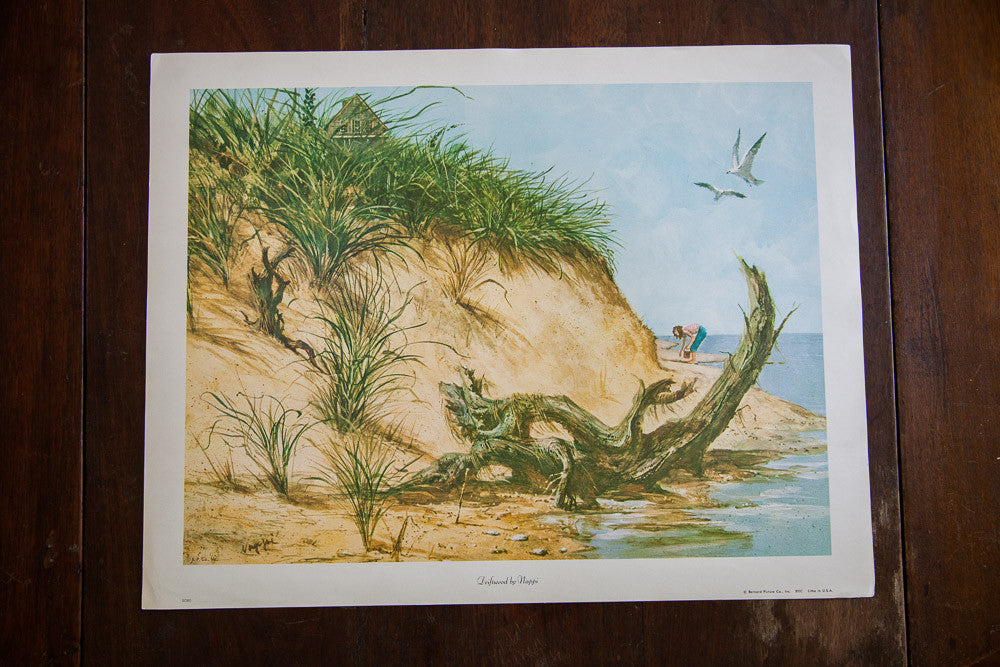 Vintage beach scene lithograph of a grassy sand dune, driftwood, and a woman collecting shells.