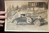 Hand holding antique car photograph, highlighting its curled edge and aged paper.