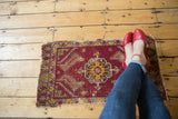 Tattered deep red antique Turkish mat with a central geometric medallion.