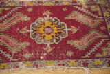 Frayed fringe and time-softened red pile on the antique Turkish mat's edge.