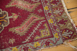 Antique Turkish mat corner: geometric red field, grey-blue border with yellow motifs, and frayed fringe.