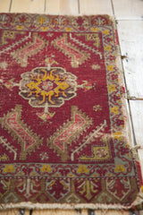 Geometric motifs and worn deep red pile on an antique Turkish mat's tattered edge.