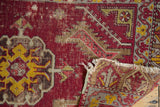 Close-up of early 20th century Turkish rug, revealing worn ruby pile, geometric motifs, and foundation weave.