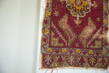 Tattered lower right corner of antique Turkish mat, showcasing red, yellow, green geometric patterns.