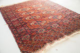 Tekke rug corner detail: madder red, aubergine geometric border, partially intact fringe.