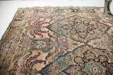 Expressive leaf motifs on an antique Kerman rug in aged ivory, deep red, and blue.