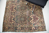 Antique Persian Kerman rug's corner detail, featuring expressive leaf designs in muted blue, purple, and aged ivory.