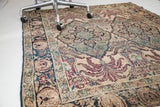 Time-softened blue, purple, and ivory floral motifs on an antique Kerman rug border.