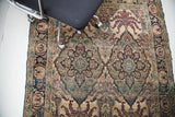 Antique Persian Kerman rug detail, displaying ornate medallion and leaf motifs in deep blue, burgundy, and ivory.