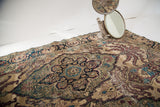 Worn patina and intricate leaf design in purple and blue on an antique Kerman rug.