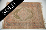 Unique green field, intricate floral medallion, and softened pile on this Turkish silk rug.