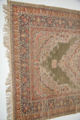 Corner close-up: green silk pile worn to knot base, intricate red and indigo borders, light fringe.
