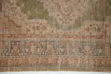 Intricate green and red motifs with worn, low pile on the vintage Turkish rug.