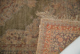 Kayseri silk rug, corner folded revealing worn green pile, fringe, and knotted back.