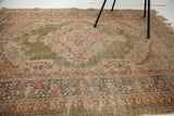Kayseri silk rug corner with worn green field, intricate borders, and short fringe.