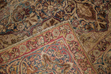 Unusual red cloudband border and worn indigo floral field of an antique Kerman rug.