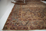 Antique Kerman rug corner: intricate cloudband border in deep reds, indigo, with overall wear.