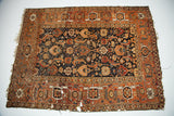 Antique Caucasian rug showing detailed herati design, rust border, walnut field, and visible storied wear.