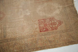 Blanched Turkish silk rug with worn red floral panel, visible foundation, and paisley border.