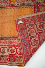 Folded corner of vintage Ladik type Anatolian rug, vibrant orange field, cranberry red border.