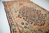 Curvilinear dark blue medallion and rust arabesques on antique ivory Senneh Baft rug.